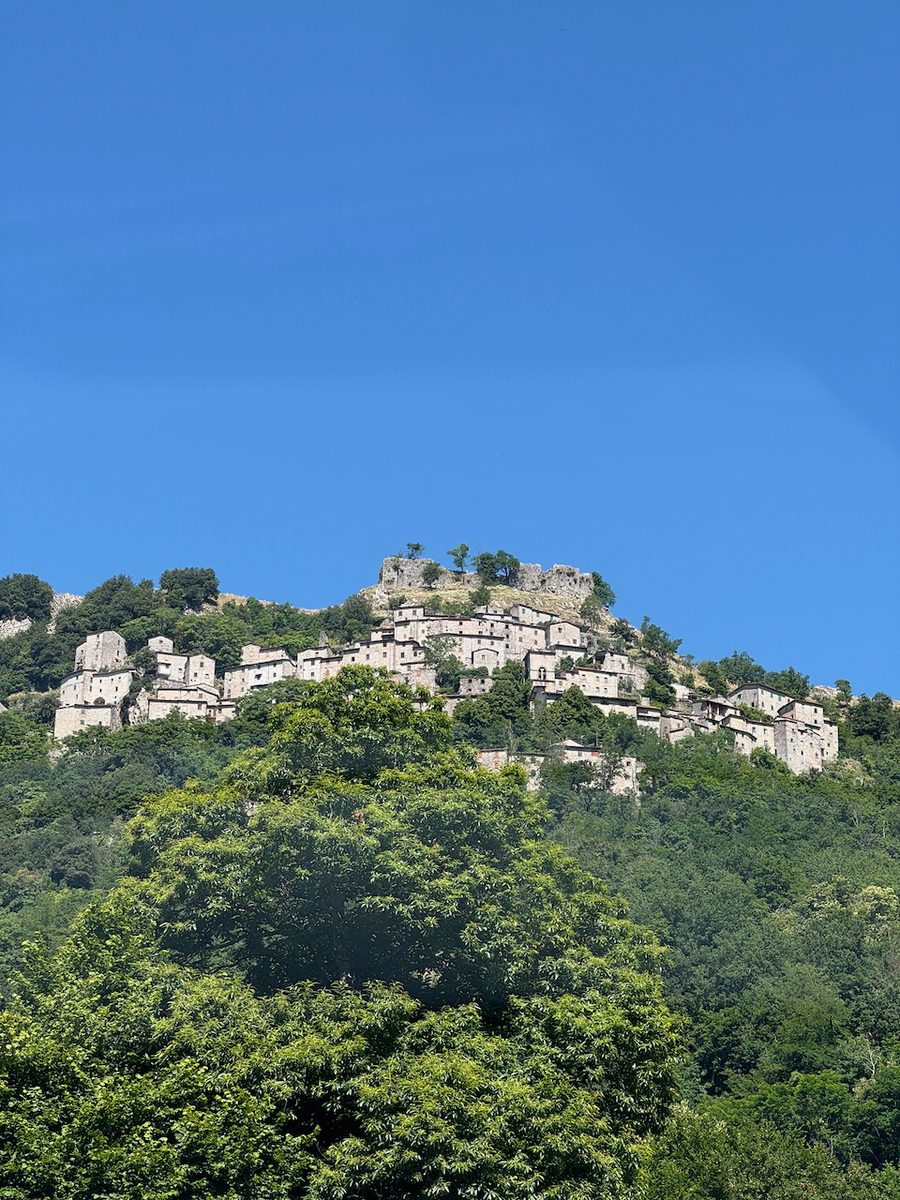 Das Bergdorf Lucchio mit der Burgruine Rocca di Lucchio auf dem Felsen gegen blauen Himmel, Val di Lima, Toskana
